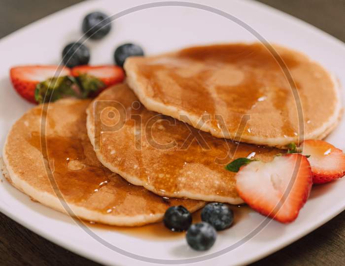 Pancakes with fresh sliced strawberry served in white plate