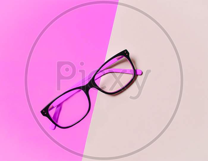 pink eyeglasses on a pink background