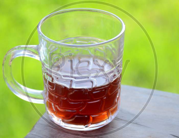 The Black Lemon Tea In The Glass Cup On The Wooden Brown And Green Background.