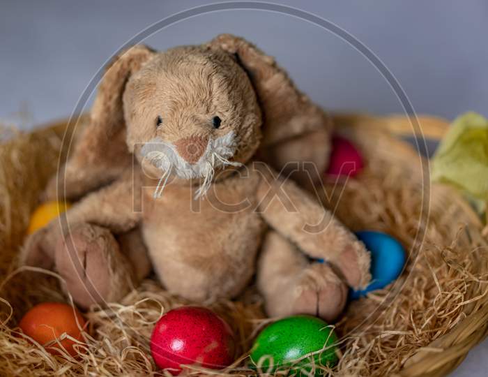 Stuffed Easter Bunny In Hay Basket And Eggs.