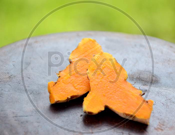 The Slice Brown Orange Ripe Turmeric On The Green Brown Wooden Background.