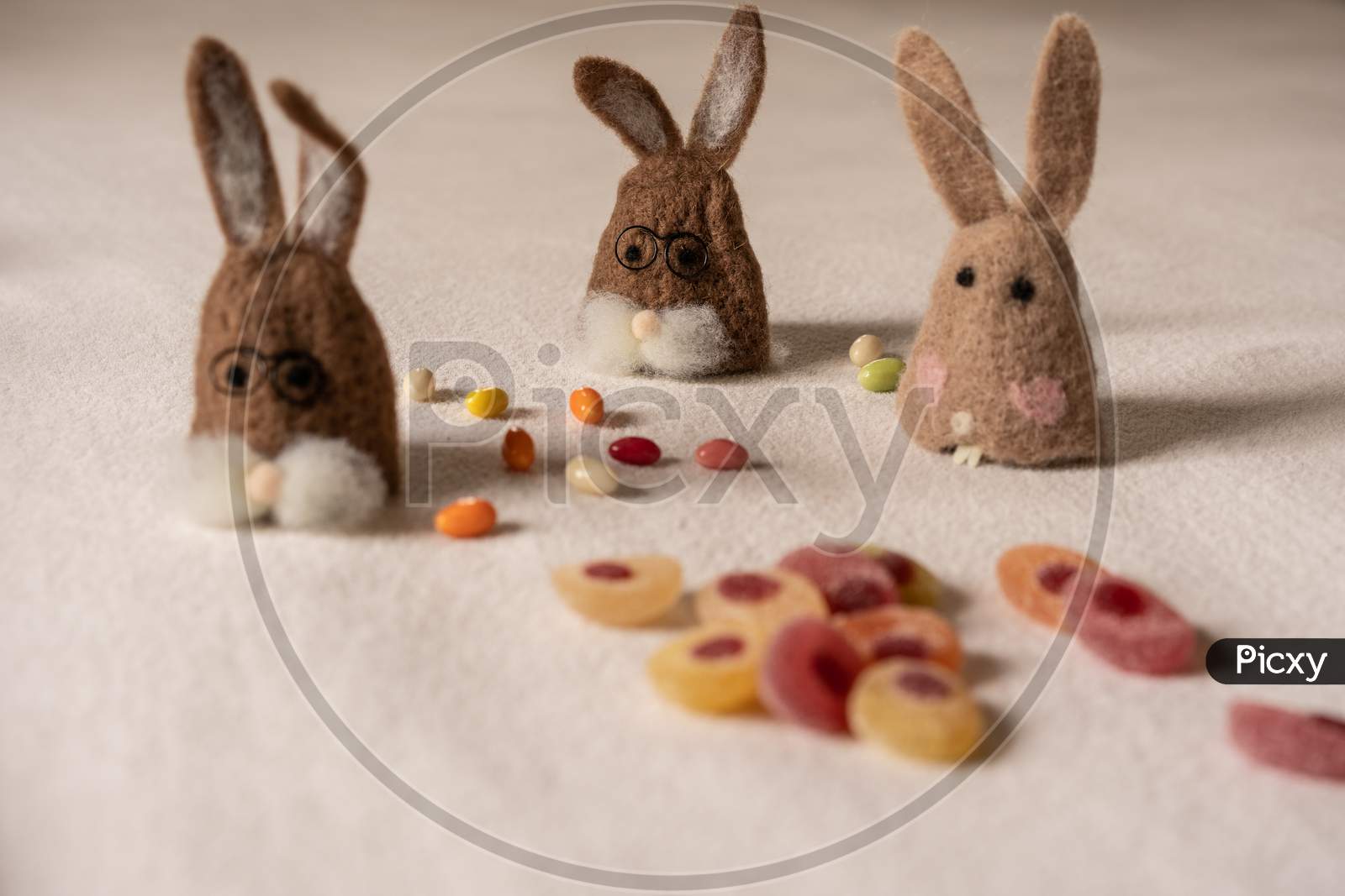 Three Bunnies Sitting Between Candys.