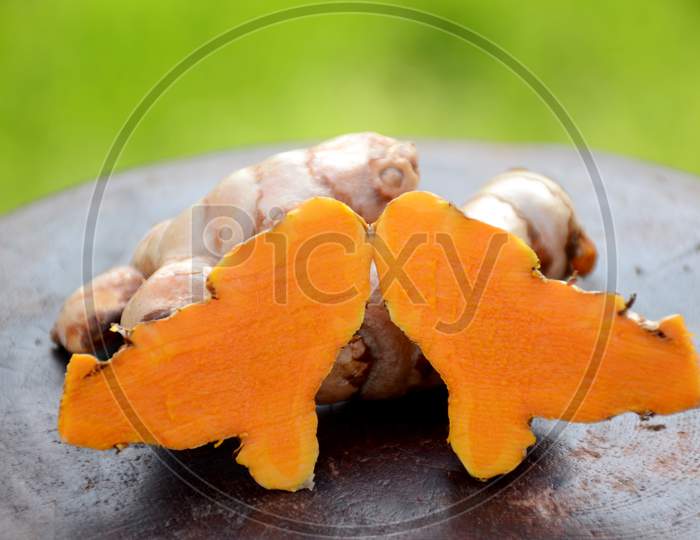The Slice Brown Orange Ripe Turmeric On The Green Brown Wooden Background.