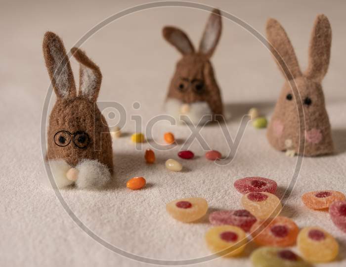 Three Bunnies Sitting Between Candys.