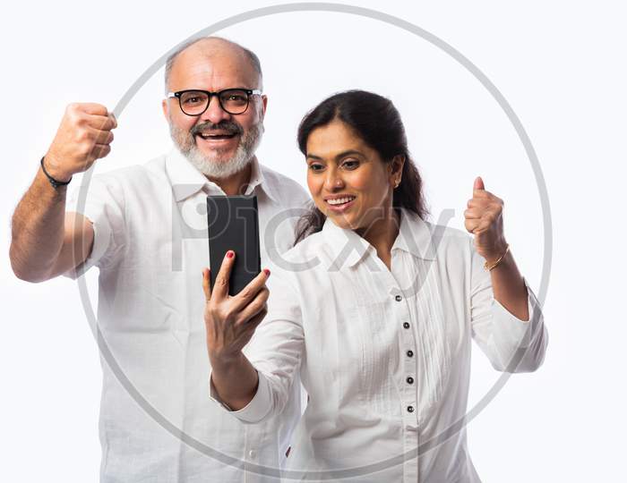 Happy Asian Indian Matured Couple Holding, Using Smartphone Against White Background