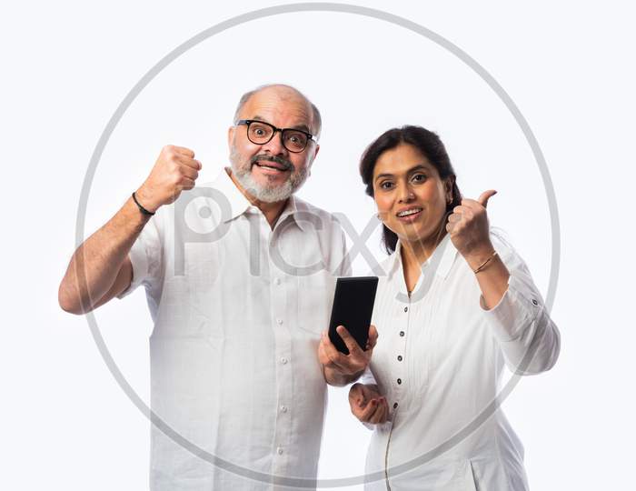 Happy Asian Indian Matured Couple Holding, Using Smartphone Against White Background