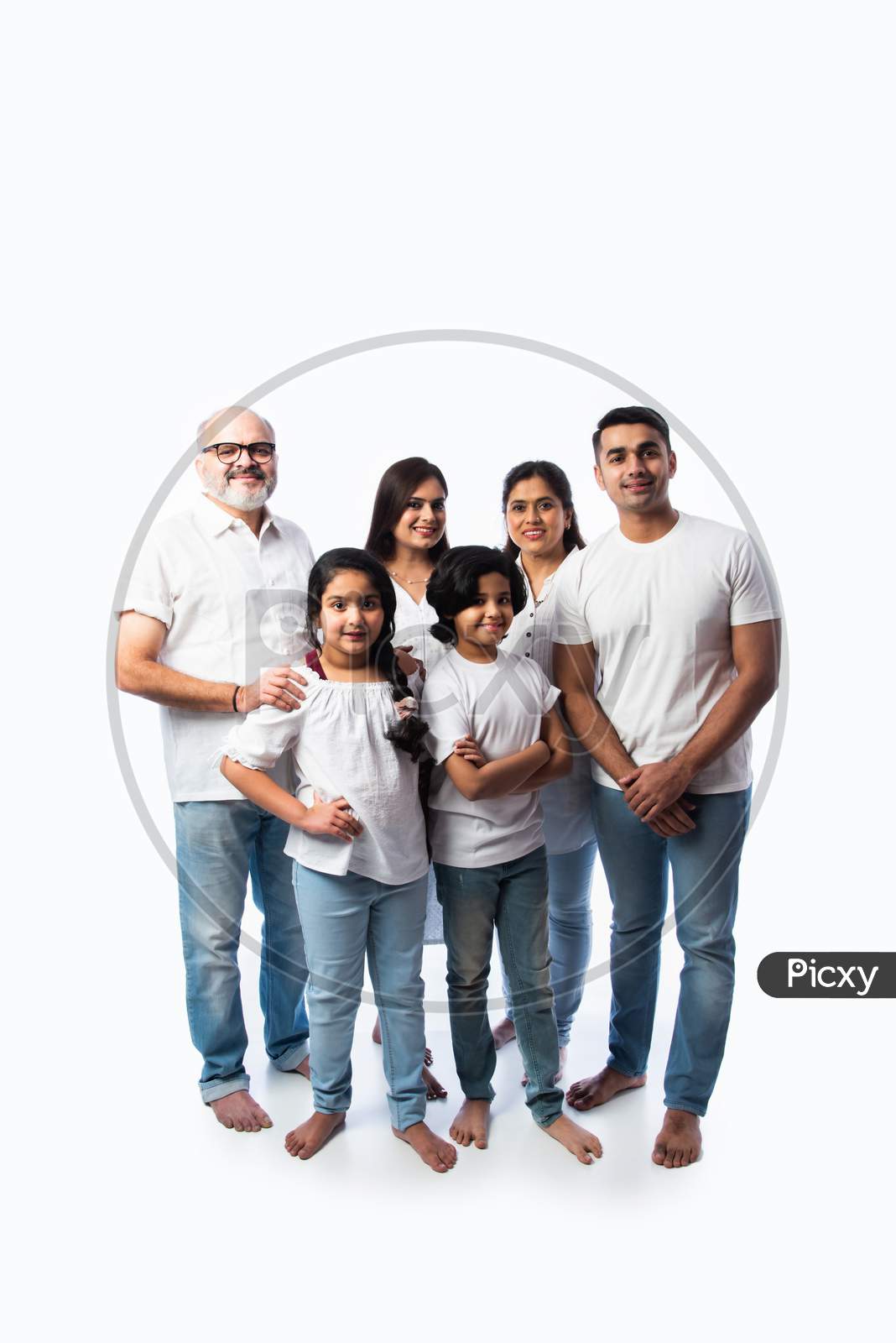 Portrait Of Indian Family With Grandparents, Parents & Kids Against White Background In White Cloths