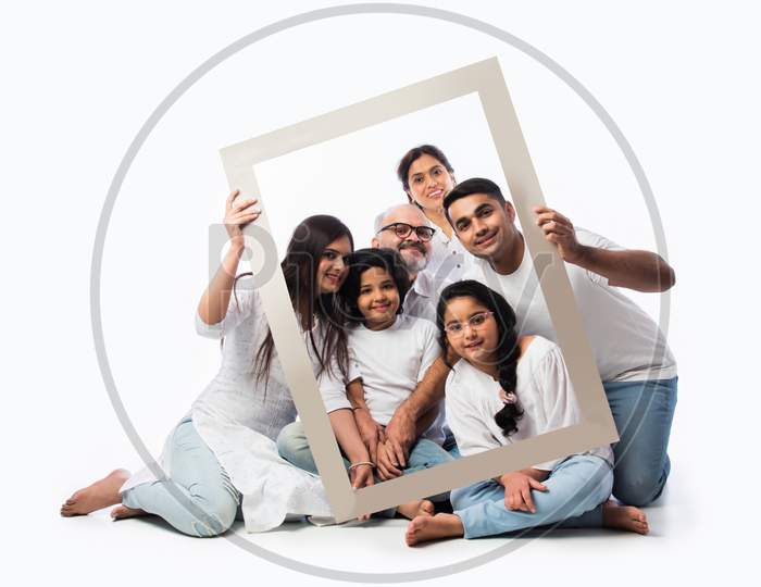 Indian Family Of Six Looking Through Or Holding Empty Frame Against White Background