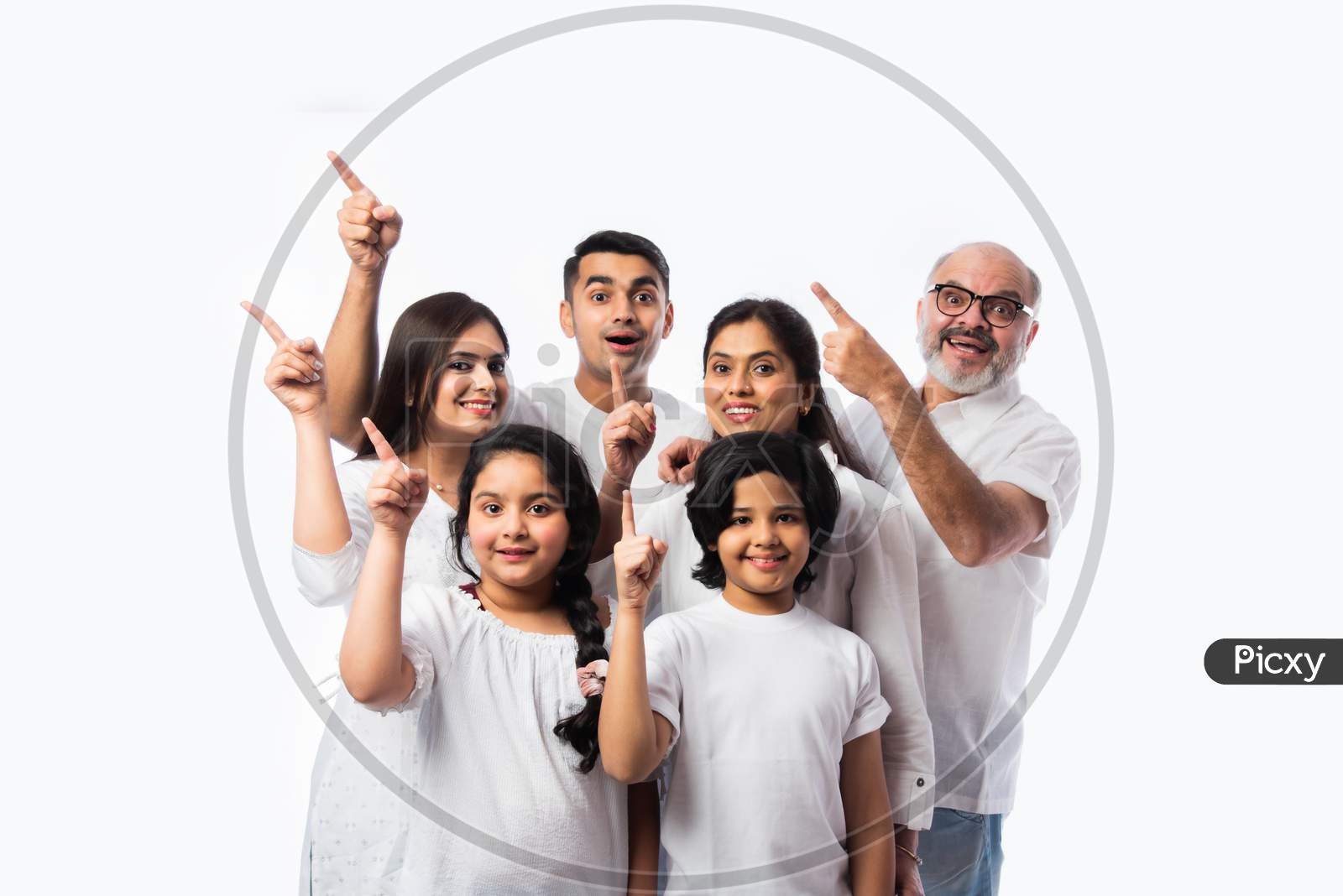 Asian Indian Family Of Six Presenting Or Pointing Empty Space While Standing Against White Backdrop