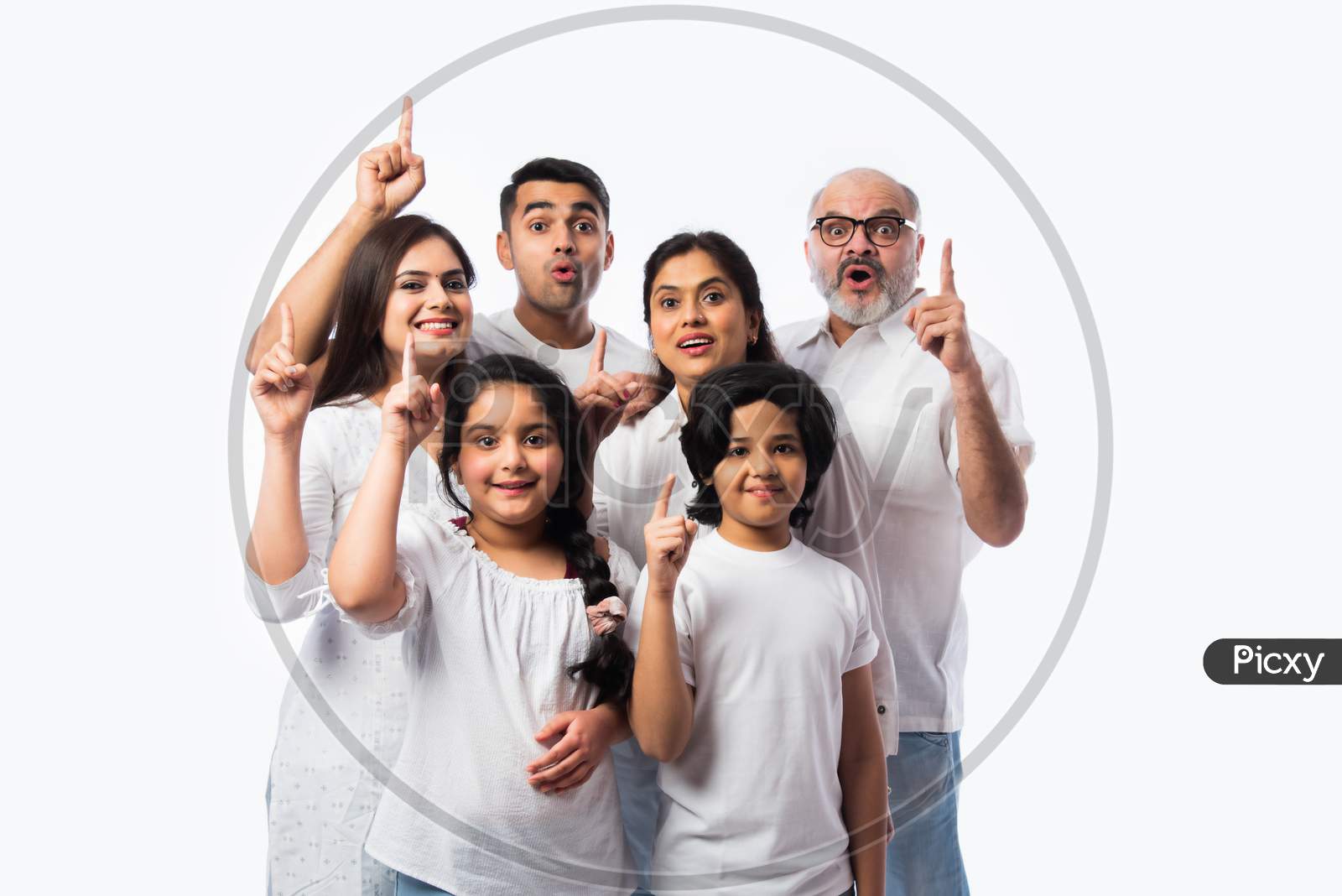 Asian Indian Family Of Six Presenting Or Pointing Empty Space While Standing Against White Backdrop