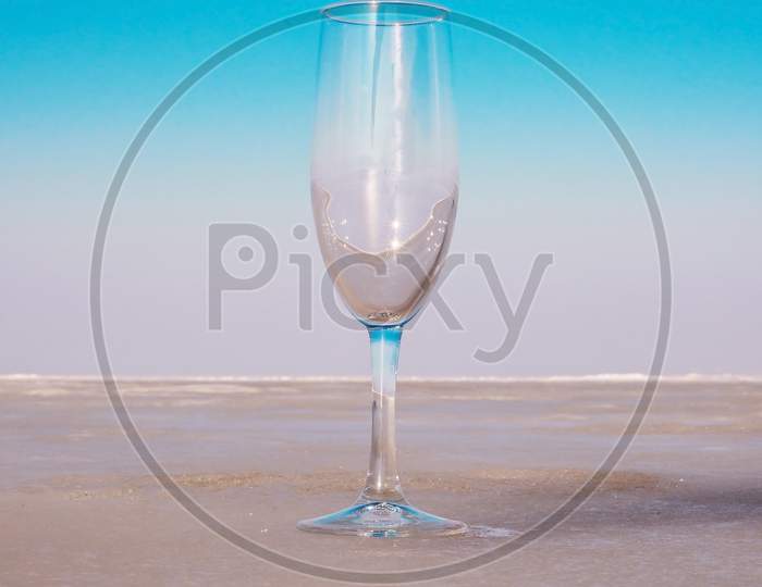 Empty wineglass goblet on beige surface against blue sky background