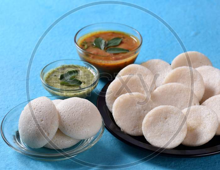Idli With Sambar And Coconut Chutney On Blue Background, Indian Dish : South Indian Favourite Food Rava Idli Or Semolina Idly Or Rava Idly, Served With Sambar And Green Coconut Chutney.