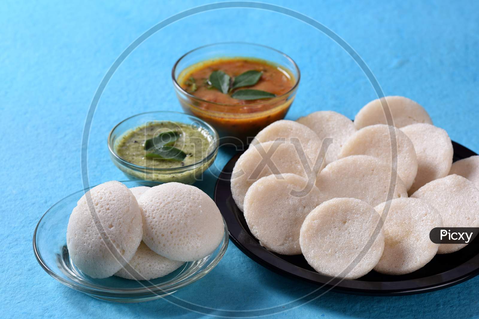 Idli With Sambar And Coconut Chutney On Blue Background, Indian Dish : South Indian Favourite Food Rava Idli Or Semolina Idly Or Rava Idly, Served With Sambar And Green Coconut Chutney.