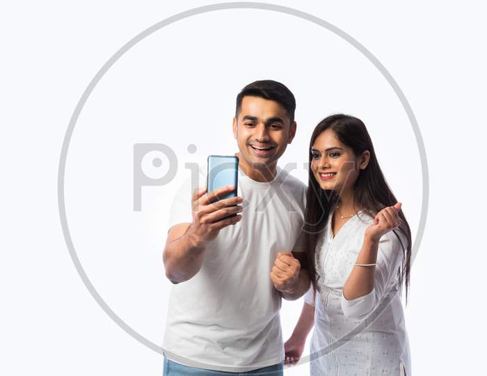 Indian Asian Smart Young Couple Holding Using Smartphone Against White Background