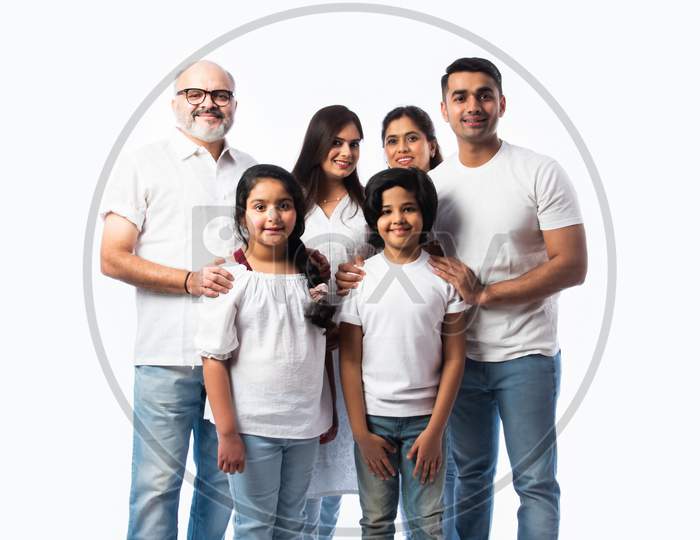 Portrait Of Indian Family With Grandparents, Parents & Kids Against White Background In White Cloths