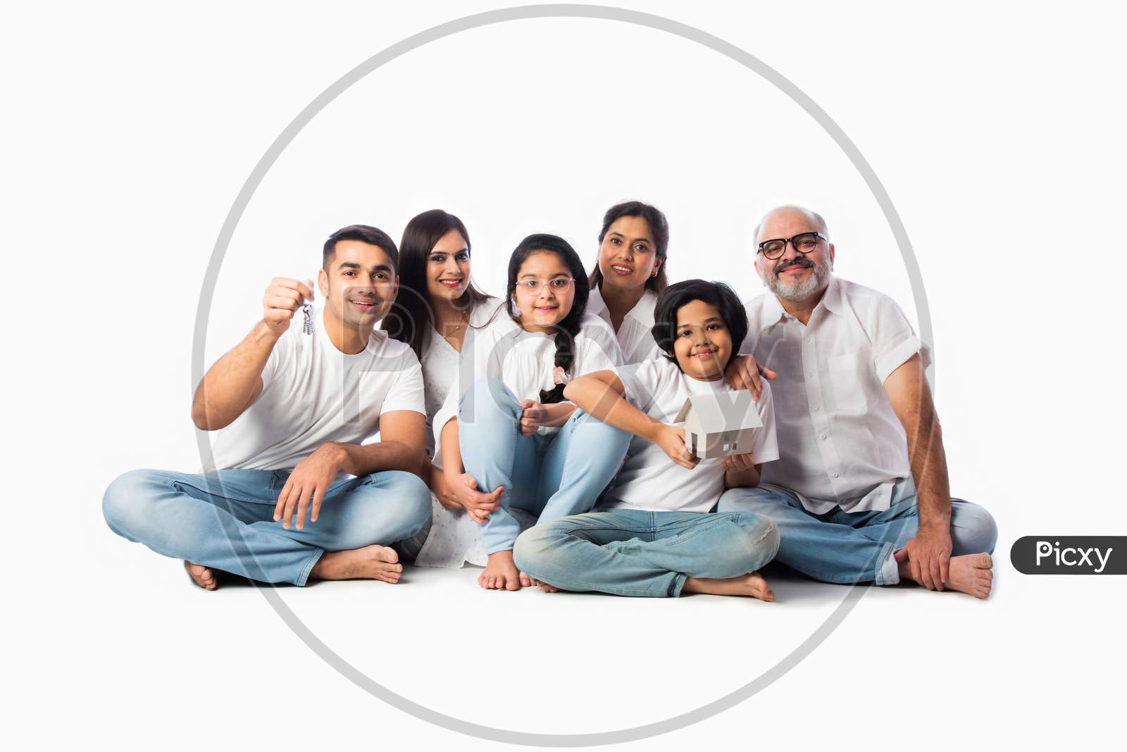 Asian Indian Family Of Six Holding Paper House Model With Keys, Isolated Against White Background