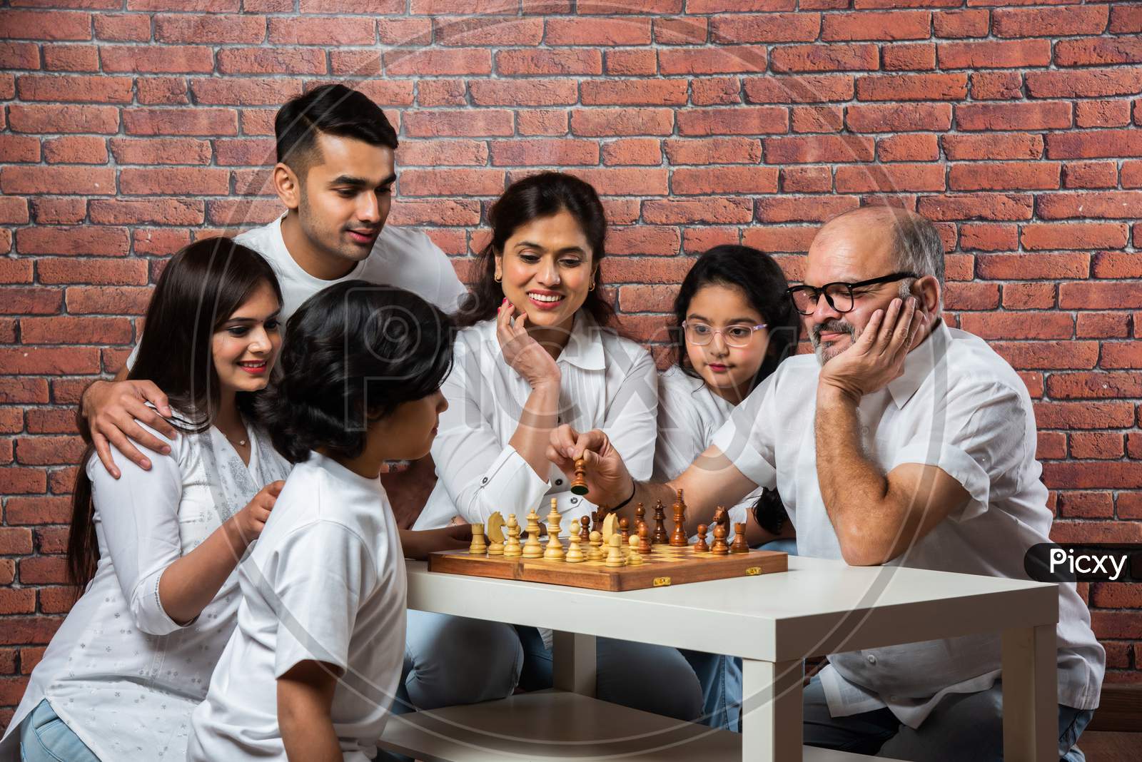 Indian Asian Multigenerational Family Playing Chess Indoor At Home In White Cloths
