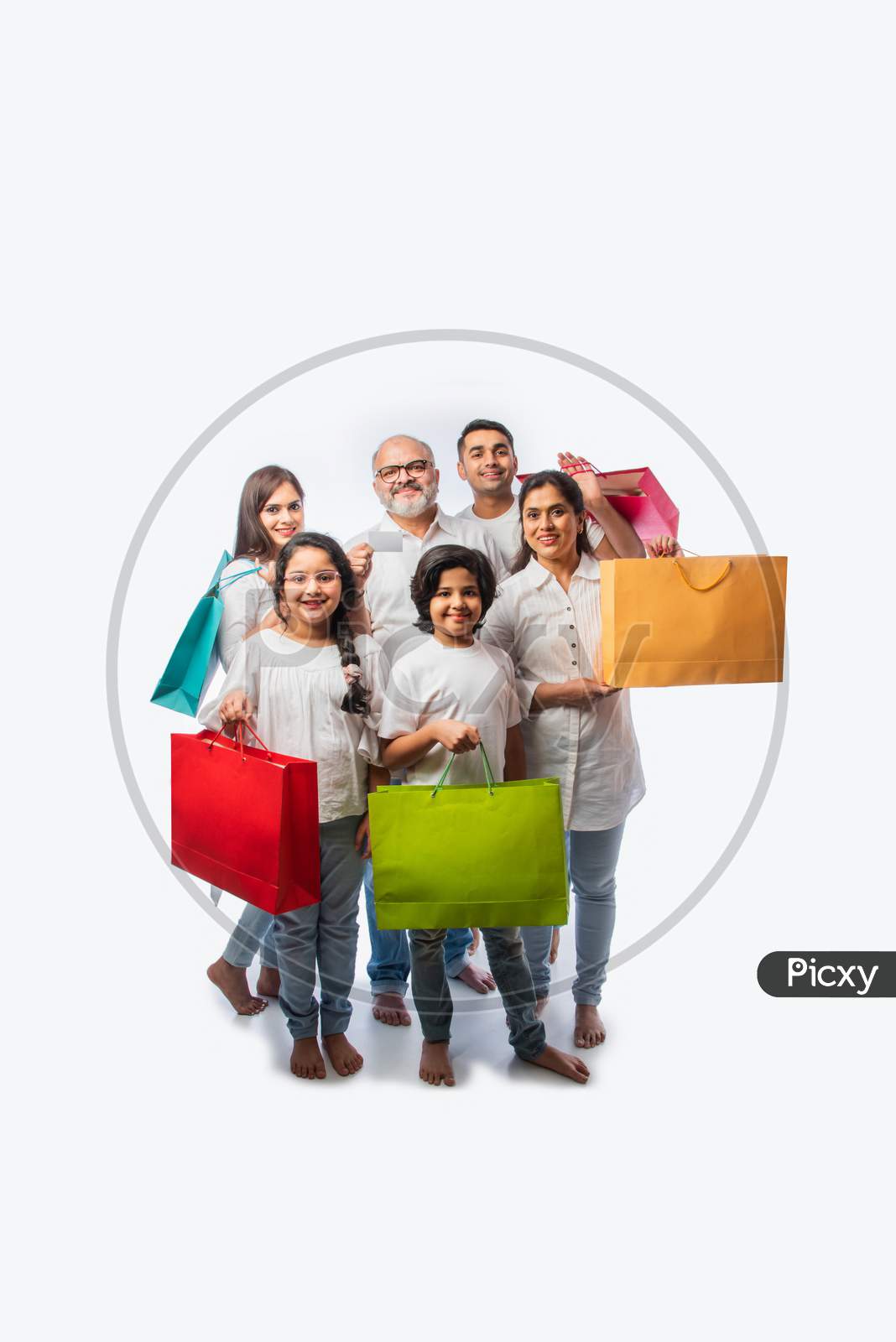 Indian Family With Shopping Bags Includes Young Parents, Grand Parents And Kids Against White
