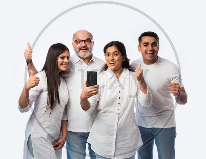 Indian Family Using Smartphone, Includes Young Couple And Senior Adults