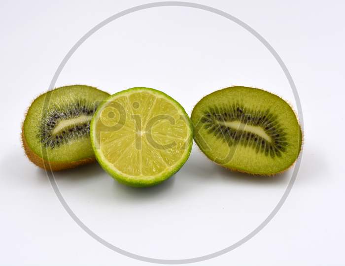Healthy ripe delicious fruits for human health. Juicy fruits of brown kiwi with limes. Two kiwi halves with one lime half are located on a white background.
