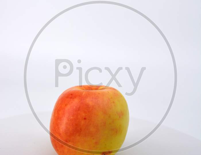 Little ripe yellow apple with red sideways located on a white background.