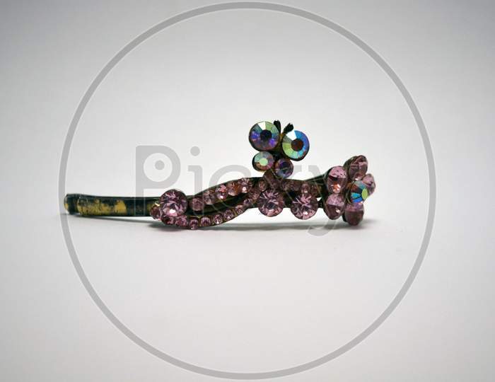 Metal female hair clip decorated with large pink beautiful stones and located on a white background.