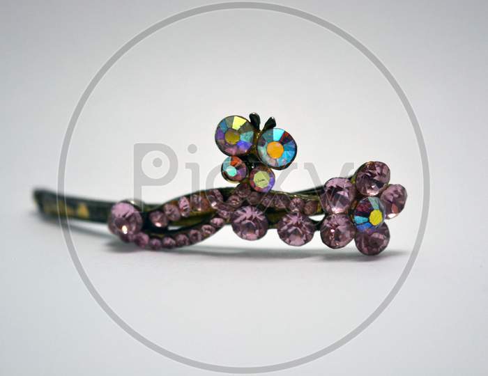 Metal female hair clip decorated with large pink beautiful stones and located on a white background.