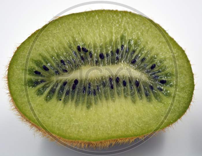 Healthy ripe delicious fruits for human health. Green kiwi fruits arranged on a white background. The whole kiwi is cut into one even piece.