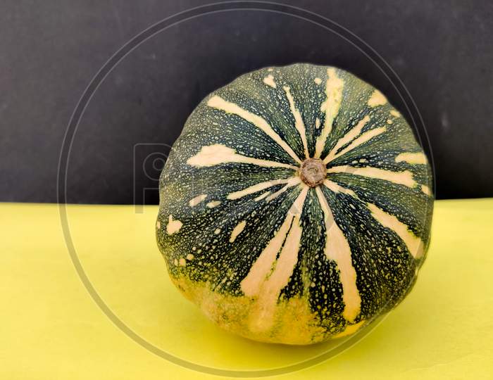 Bottom View Of Green Pumpkin Isolated On Yellow And Black Background