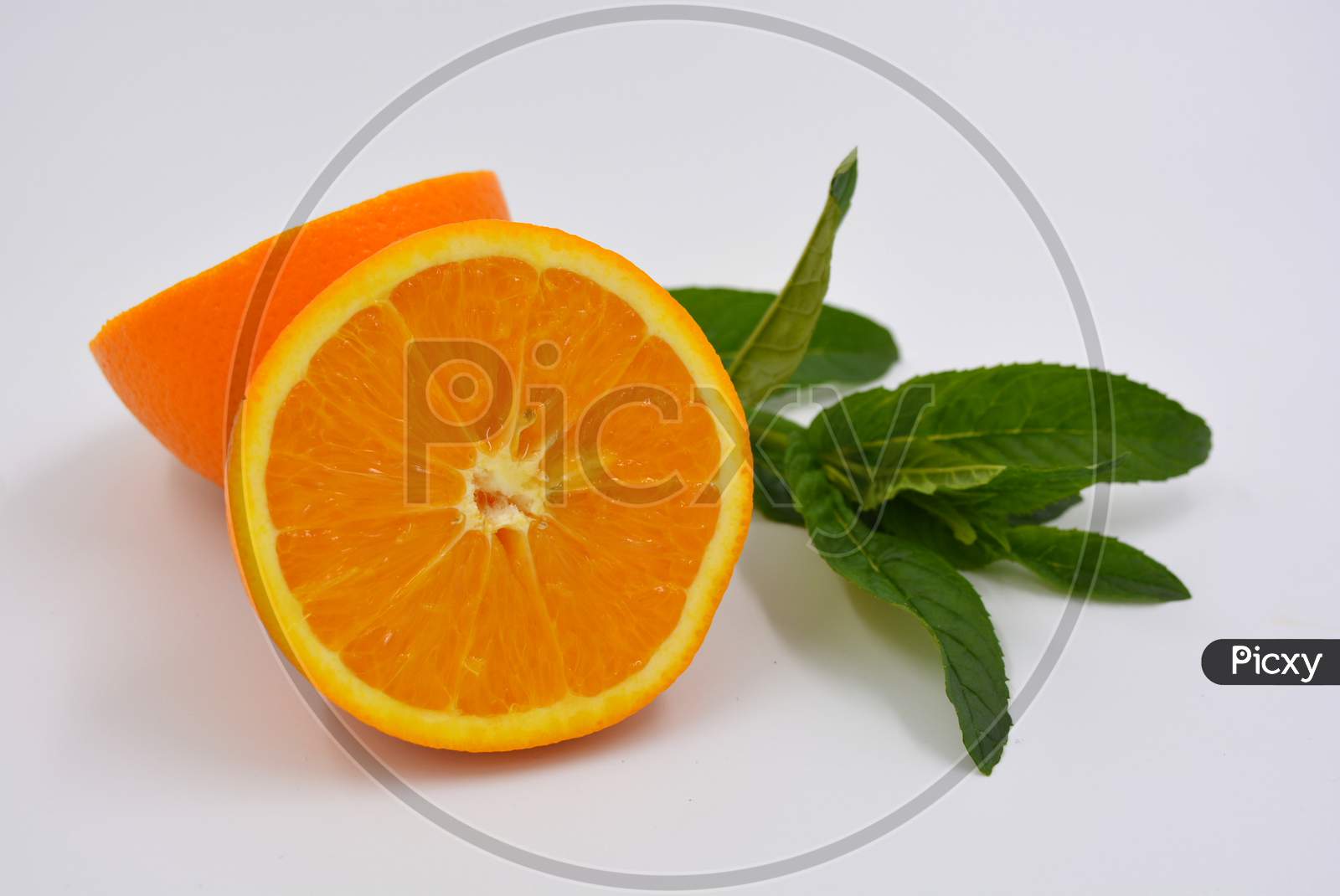 Healthy ripe delicious fruits for human health. Juicy fruits of orange orange with bright green mint. Two halves of an orange with large green leaves.