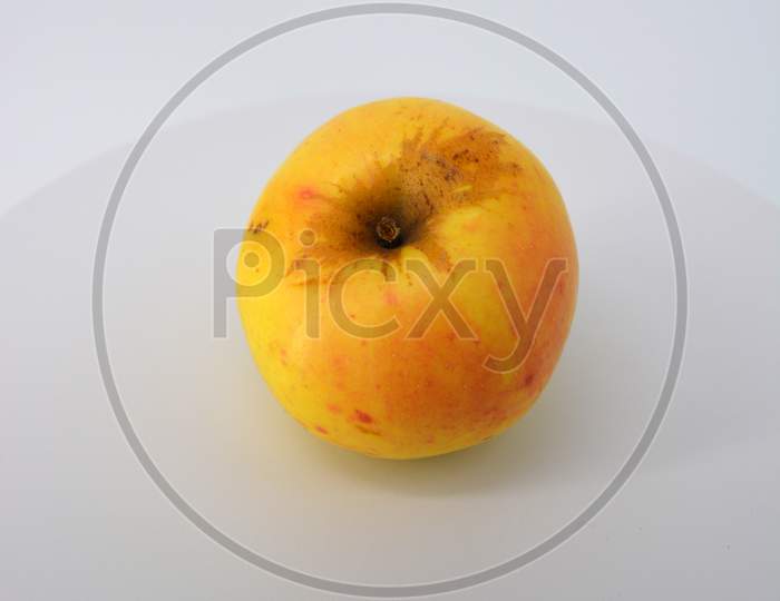 Little ripe yellow apple with red sideways located on a white background.