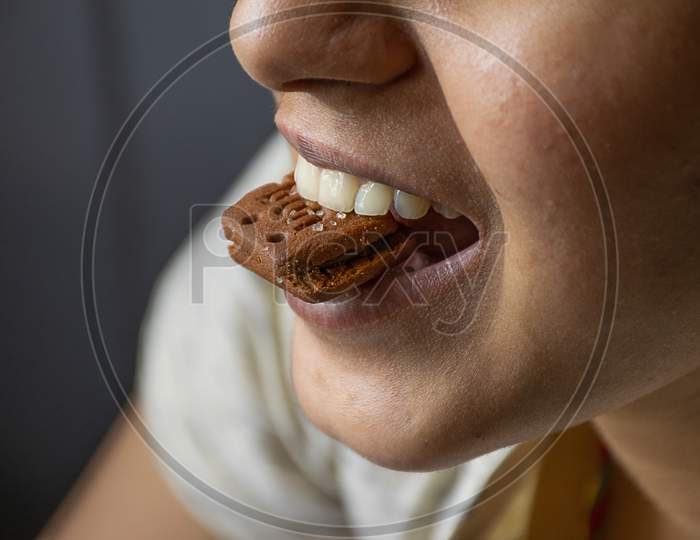 Close Up Portrait Of Happy Indian Girl Eating Chocolate Biscuit At Home.