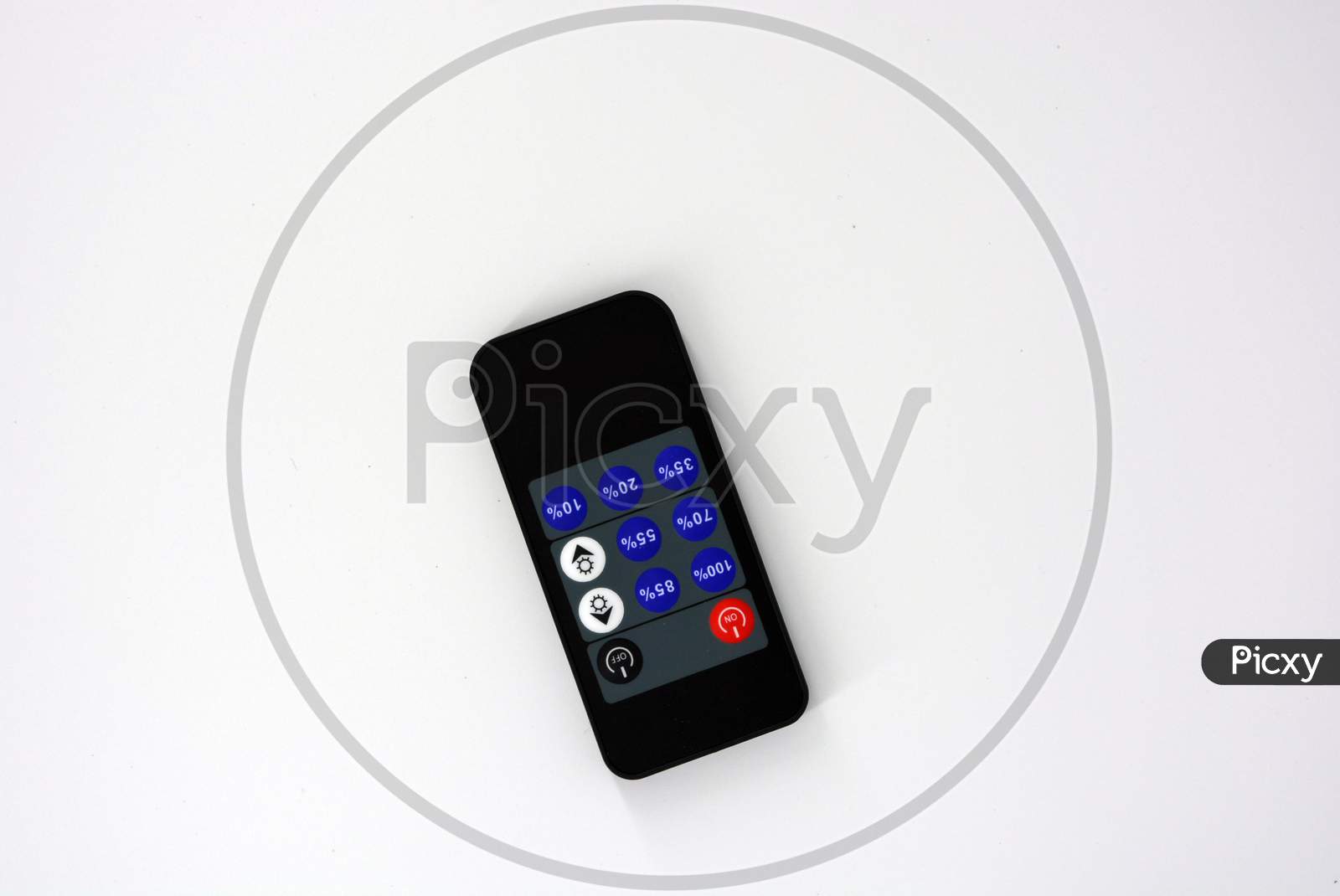 Black plastic radio remote control on batteries with colored buttons located on a white plastic background.