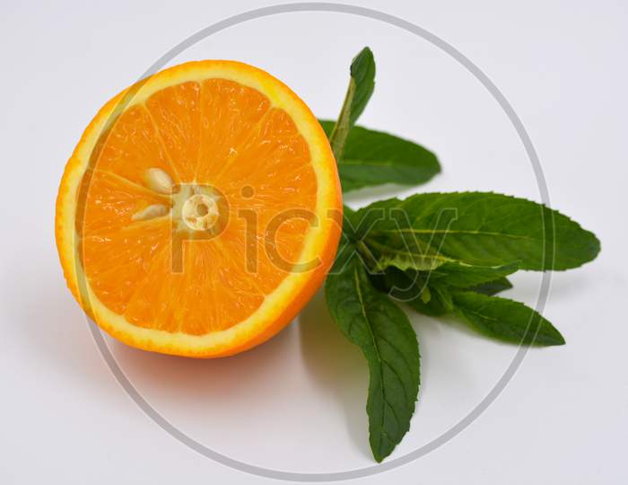 Healthy ripe delicious fruits for human health. Juicy fruits of orange orange with bright green mint. One half of an orange with large green leaves.