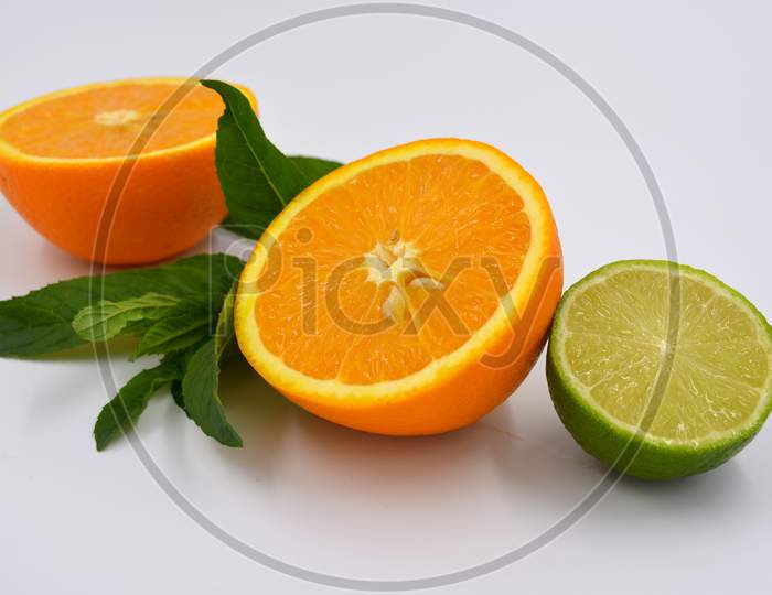 Healthy ripe delicious fruits for human health. Juicy fruits of orange orange with bright green mint. Two halves of an orange with large green leaves and one half of a lime.