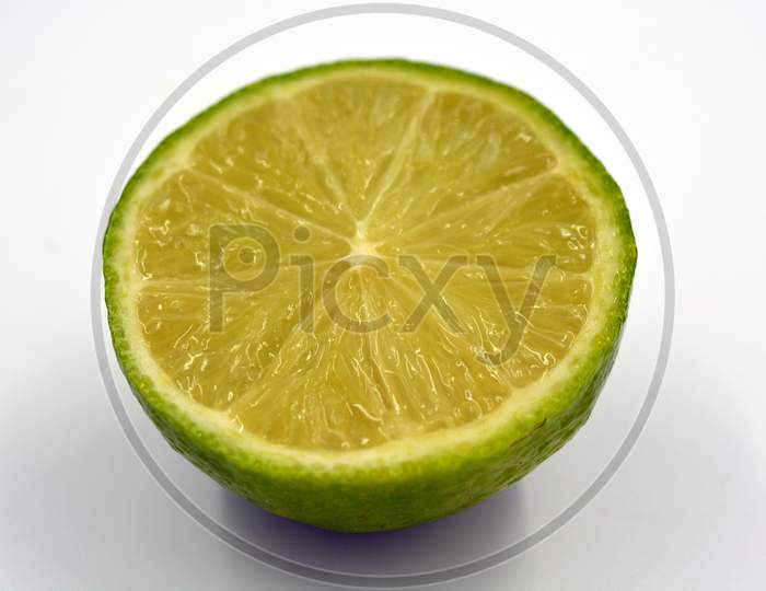 Healthy ripe delicious fruits for human health. Juicy fruits of green sour lime. One half of a sliced lime set on a white background.