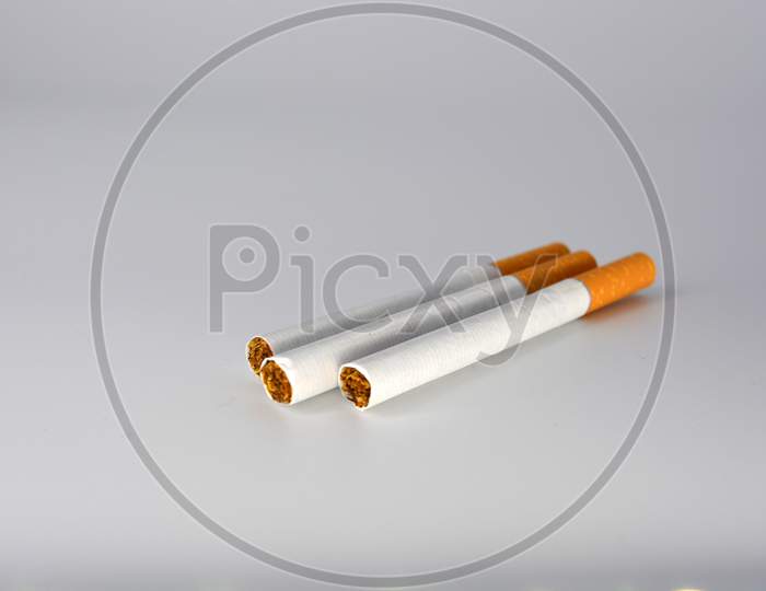 Many white cigarettes with a brown filter chaotic arranged on a white background. Smoking is blicking bad on health. Cigarettes worsen the work of the brain nerves