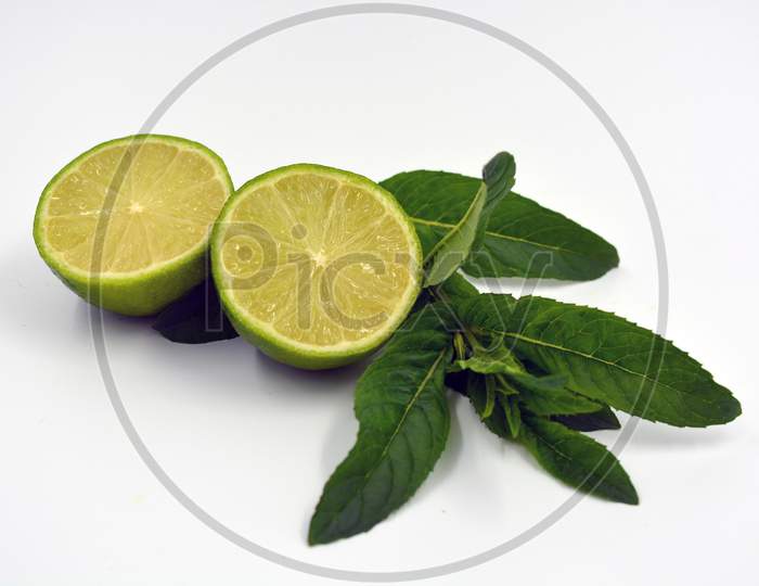 Healthy ripe delicious fruits for human health. Juicy fruits of green lime with green lime leaves. Two halves of cut lime and lime sprigs set on a white background.