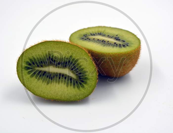 Healthy ripe delicious fruits for human health. Green kiwi fruits arranged on a white background. A whole kiwi is cut into two even pieces.