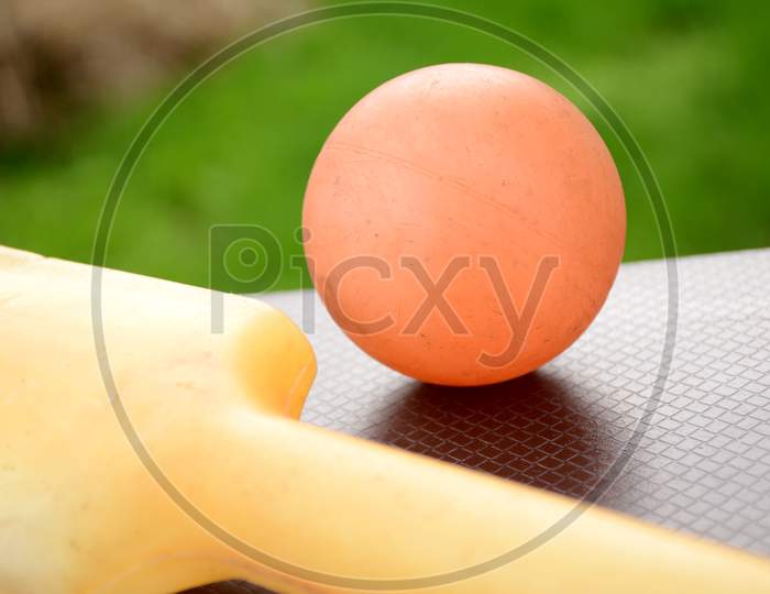 The Orange Color Old Ball With Bat On The Green Brown Background.