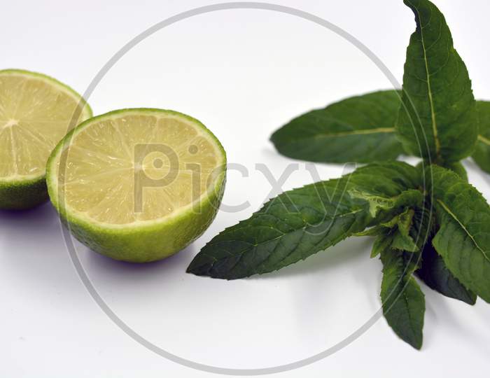 Healthy ripe delicious fruits for human health. Juicy fruits of green lime with green lime leaves. Two halves of cut lime and lime sprigs set on a white background.