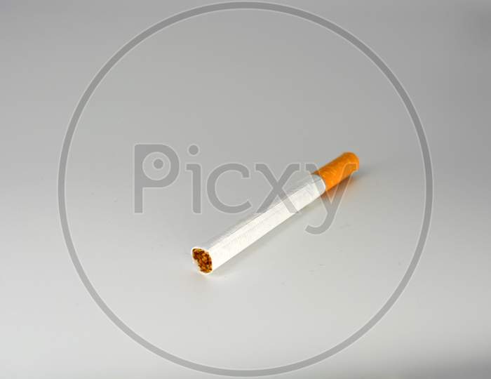 Image Of One White Cigarette With Brown Filter Located On A White
