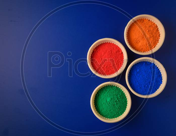 Top View Of Colorful Traditional Holi Powder In Bowls Isolated On Dark Background.Space For Text . Happy Holi.Concept Indian Color Festival Called Holi