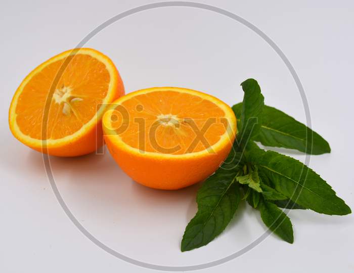 Healthy ripe delicious fruits for human health. Juicy fruits of orange orange with bright green mint. Two halves of an orange with large green leaves.