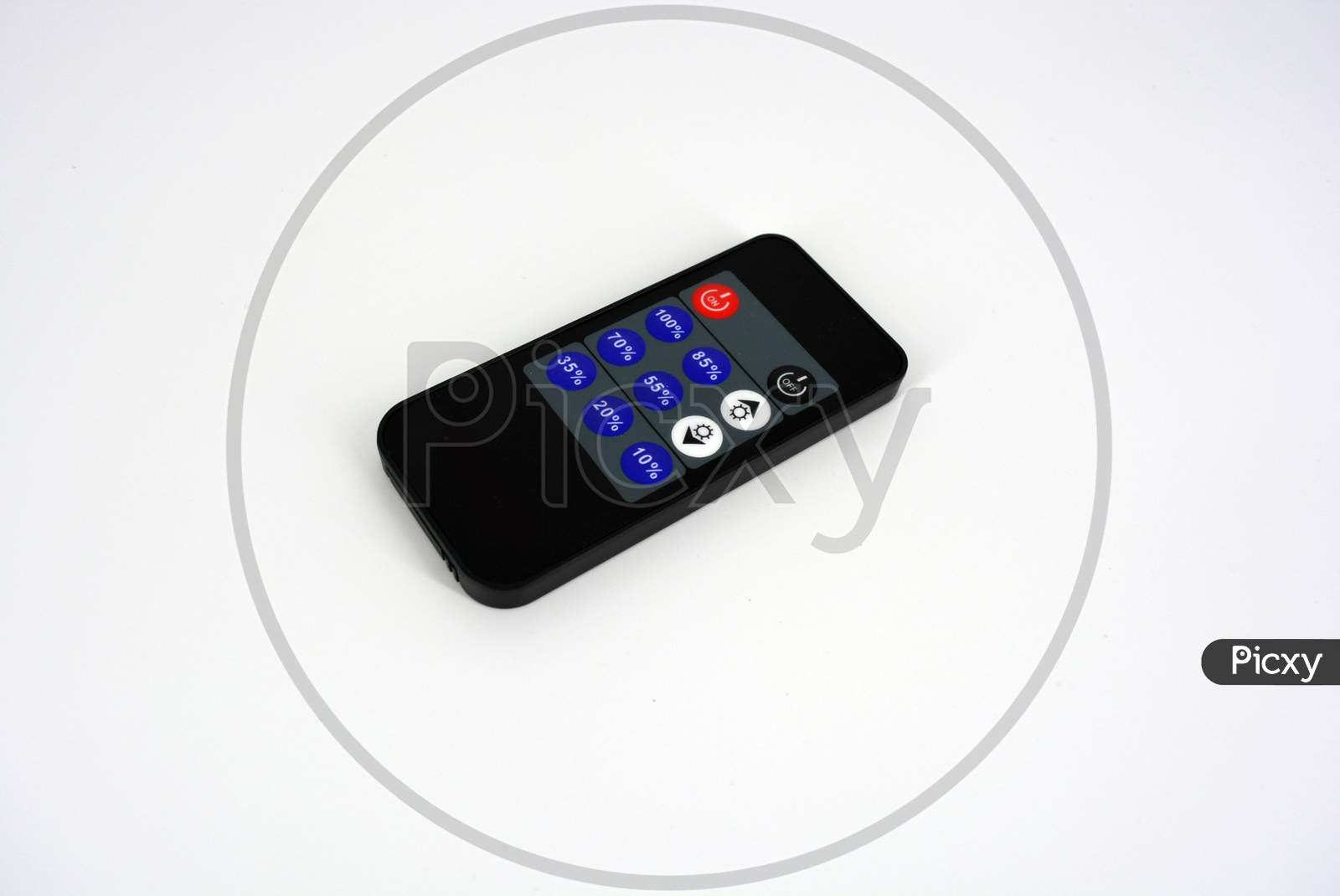 Black plastic radio remote control on batteries with colored buttons located on a white plastic background.