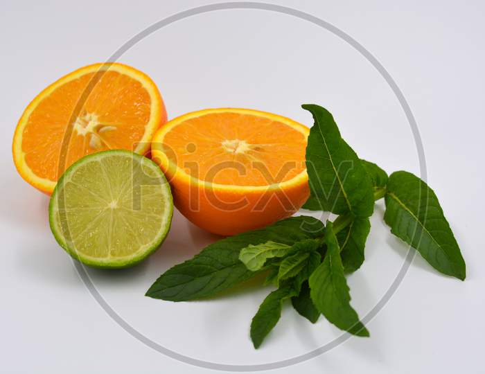 Healthy ripe delicious fruits for human health. Juicy fruits of orange orange with bright green mint. Two halves of an orange with large green leaves and one half of a lime.