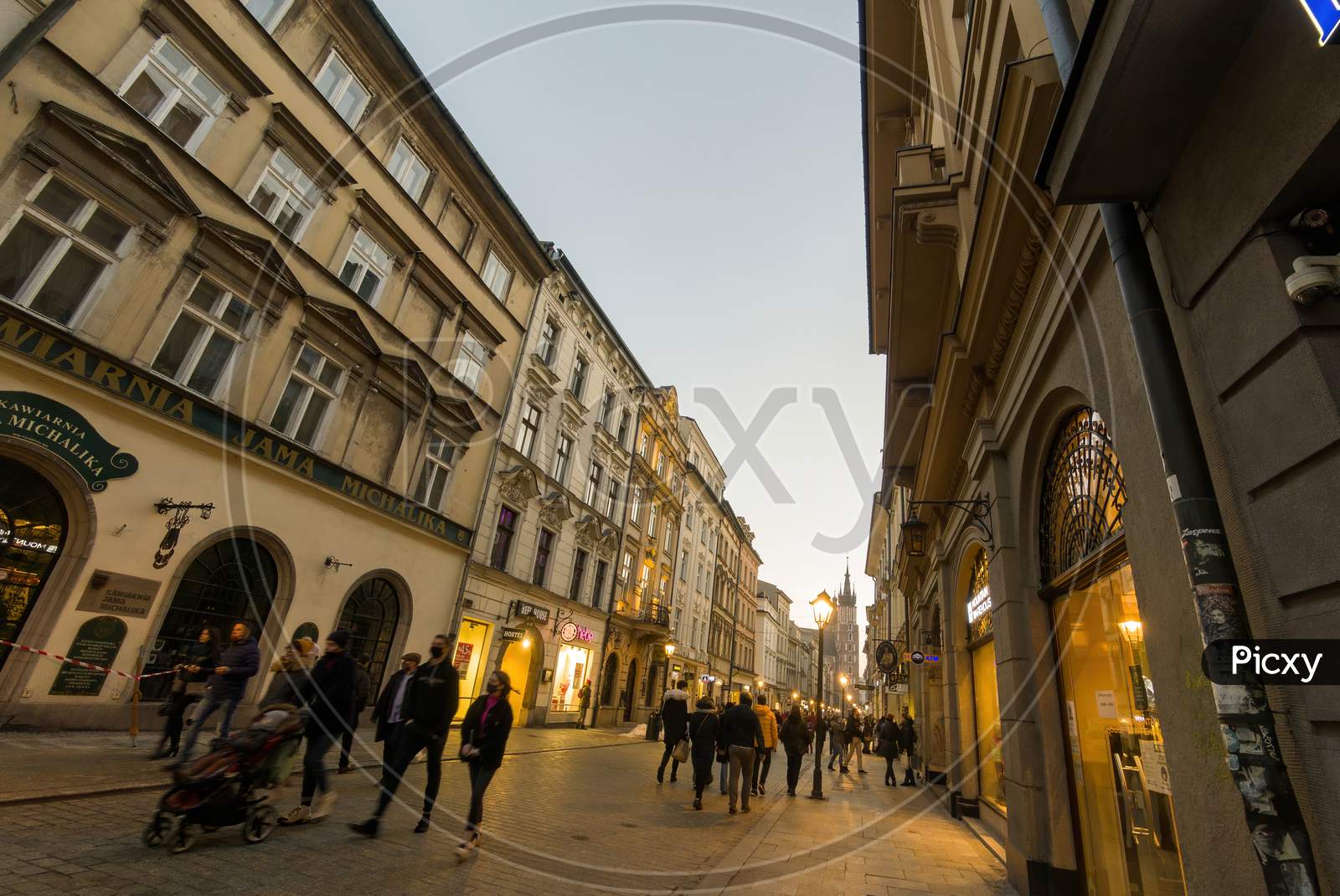 Krakow, Poland - February 20, 2021: Wide Angle Shot Of A European Street And People Taking A Walk During Evening In The Old Town Of Cracow City. People Walking On Narrow European Commercial Street