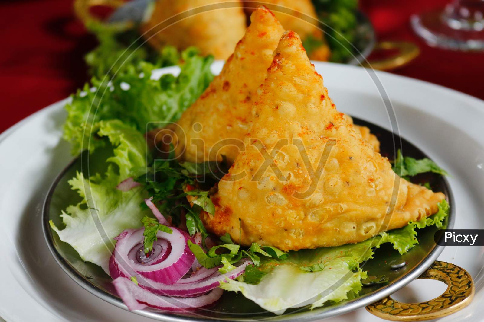 Close-Up Photo of Fried on Saucer -Samosa with Green vegetable & Onion Sliced Served.