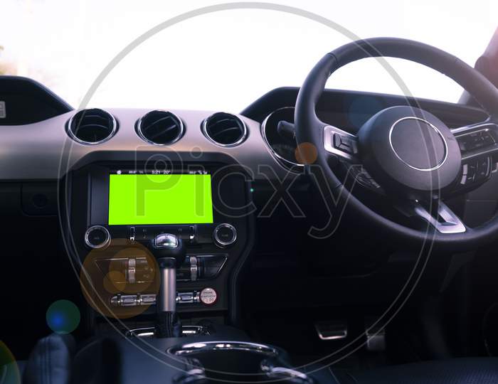 Interior Of A Luxury Car With Black Leather Finish, With A Green Screen On The Dashboard. Man Driving The Car.