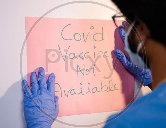 Selective Focus On Notice Board, Doctor Pasting Covid-19 Vaccine Not Available Notice On Door Front.